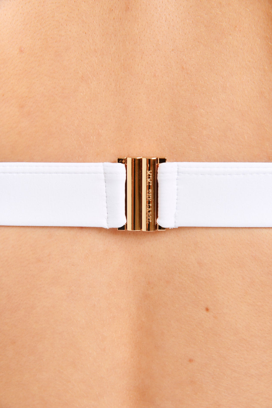 Close up of gold clasp on a white swimsuit top